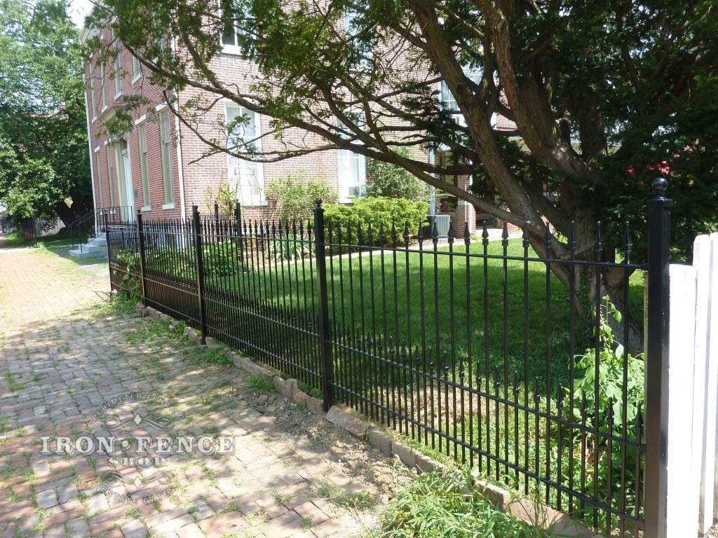 Black wrought iron fence enclosing a well-kept lawn