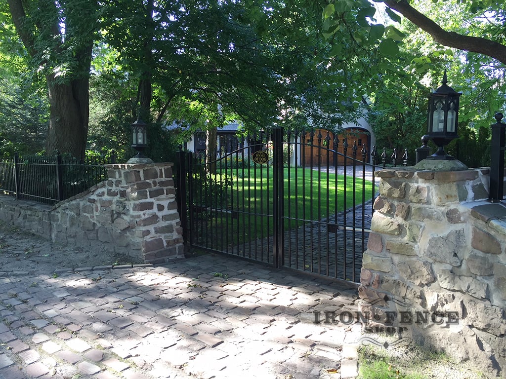 Our Signature Grade Iron Arched Driveway Gate Installed with a Stone Wall