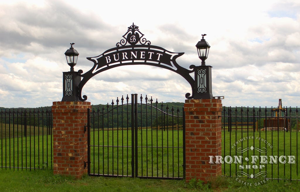 Custom iron arched double walk gate and 5ft tall Signature grade fence mounted between brick columns and under a custom arch created by Covington Iron Works (Style #1 - Classic)