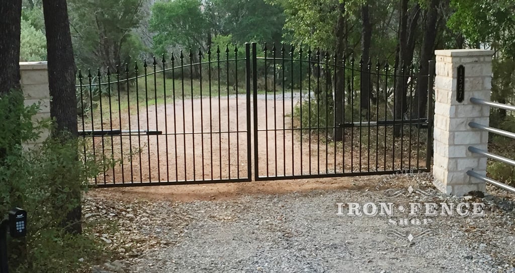 Stronghold Iron Arched Driveway Gate mounted behind Stone Columns
