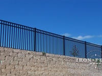 Our 54in Tall Infinity Aluminum Fence Panel in Traditional Grade on Top of a Wall