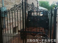 Custom iron driveway gate with decorative scroll top and puppy pickets