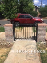 An Arched Iron Gate in 3H x 4W Size Between Brick Columns