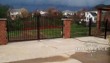 Custom 4ft arching to 5Ft iron driveway gate mounted on brick pillars with matching 4ft iron fence and walk gate (Style #1 - Classic)