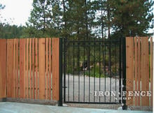 Custom 5ft tall iron gate with rings and no finials mounted between wood fencing (Style #6 - Ring Adornment)