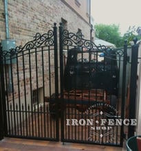 Custom iron driveway gate with decorative scroll top and puppy pickets