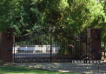 Custom iron arched driveway gate in a 6' arching to 7' height with decorative branch castings welded in