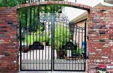 A Custom Iron Gate with Scrollwork and Motto Plate in a Brick Opening