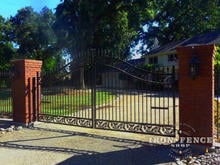 Custom 6ft arching to 7ft height driveway gate with oak castings mounted between brick pillars