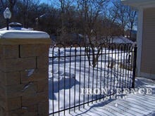 4 foot tall iron hoop and picket fence with stone pillar in winter